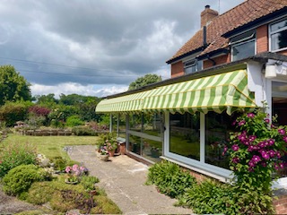 Green striped awning fitted above garden doors in Somerset
