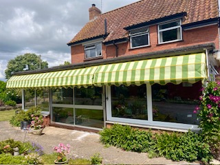 Green striped awning installed over a patio area in Somerset