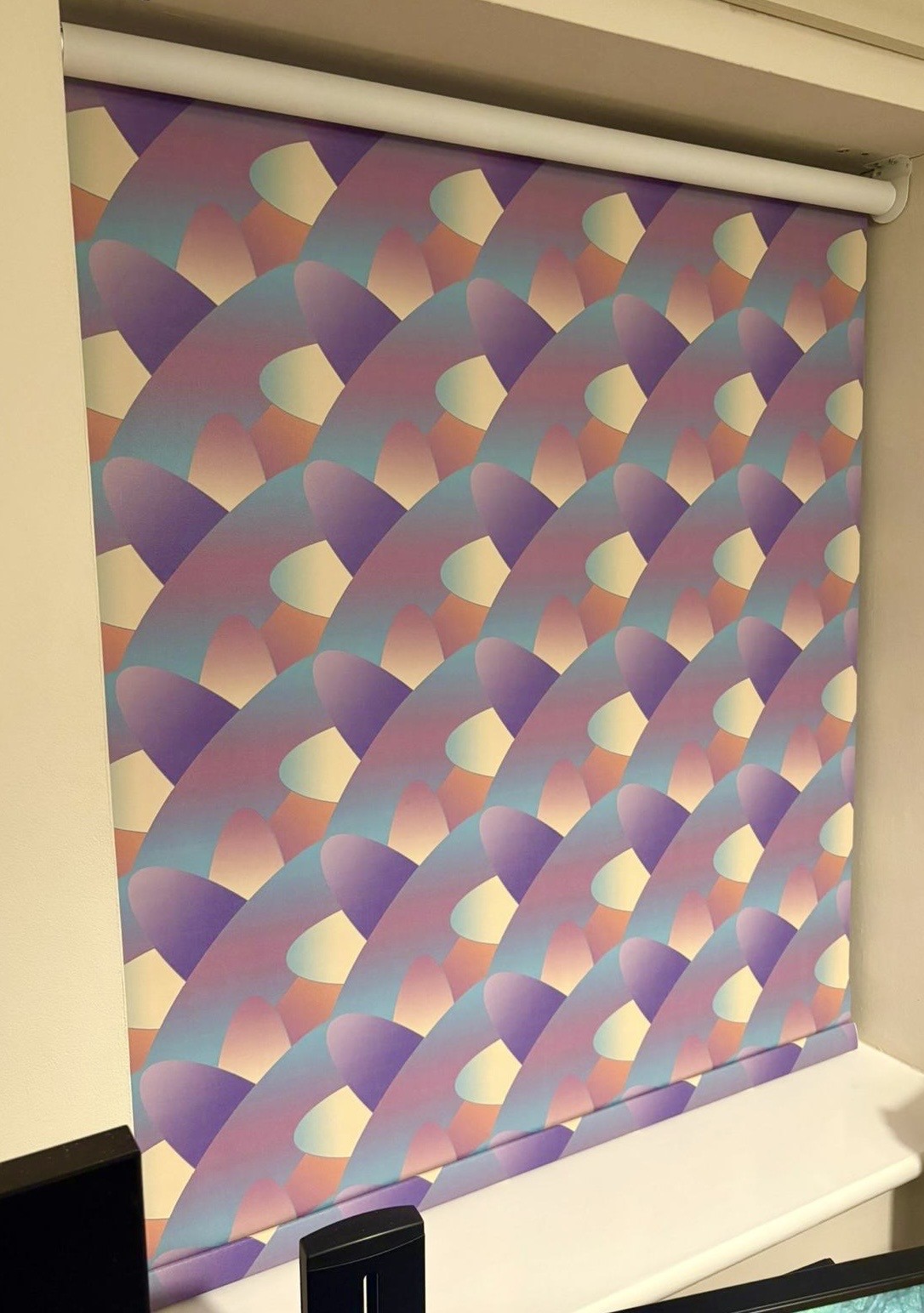 Patterned roller blind installed on a white wall window
