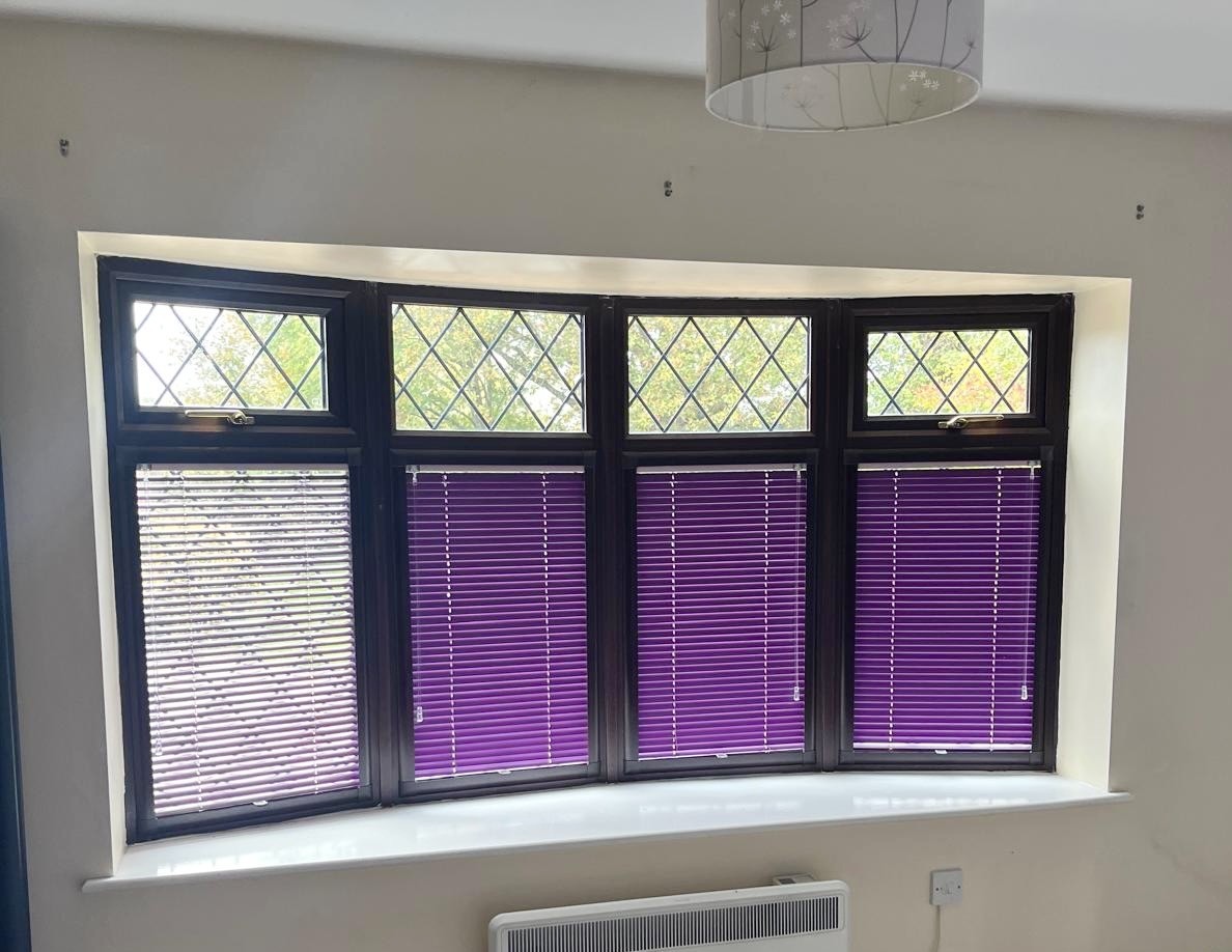 Purple venetian blind installed on a dark wood window frame