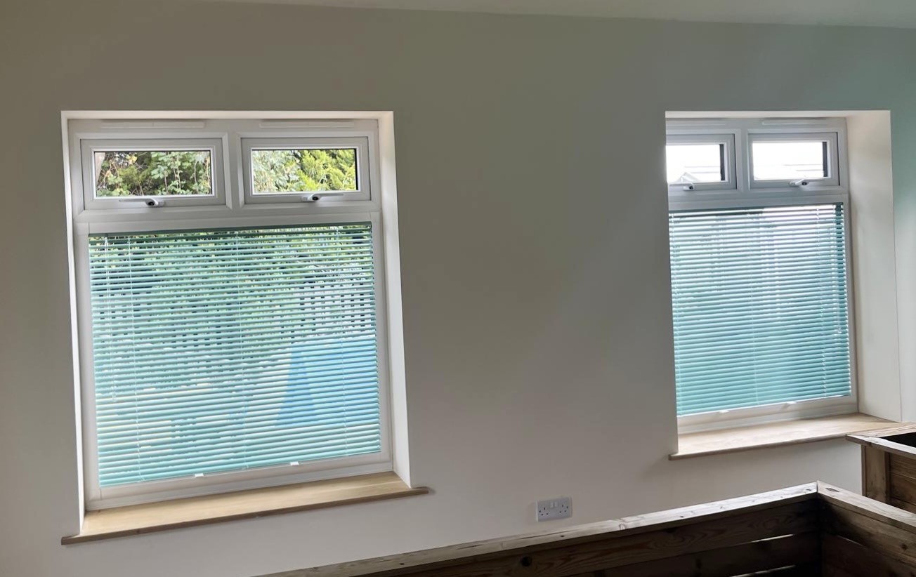Teal venetian blind installed in a bright white room