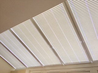 White perfect‑fit roof blinds installed on pitched conservatory ceiling windows in Somerset.