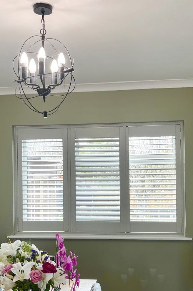 White plantation shutters fitted to a living‑room window