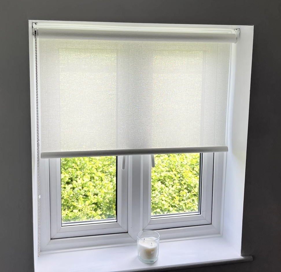 Open white roller blind installed in a grey room.