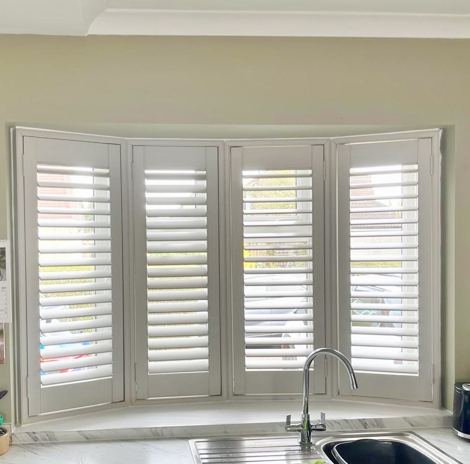 White shutters installed on a large bay window